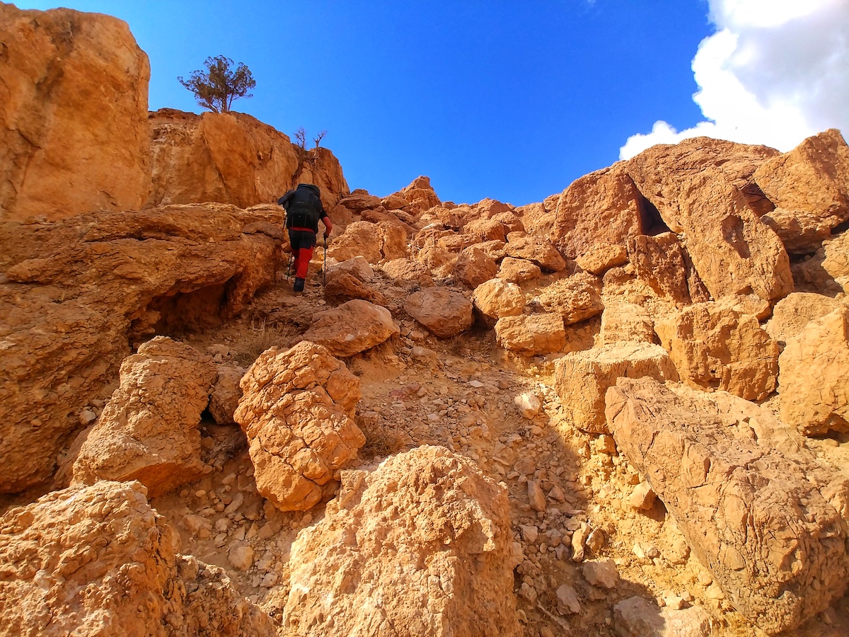 Escursionista affronta le salite rocciose del Jordan Trail tra canyon e pietraie