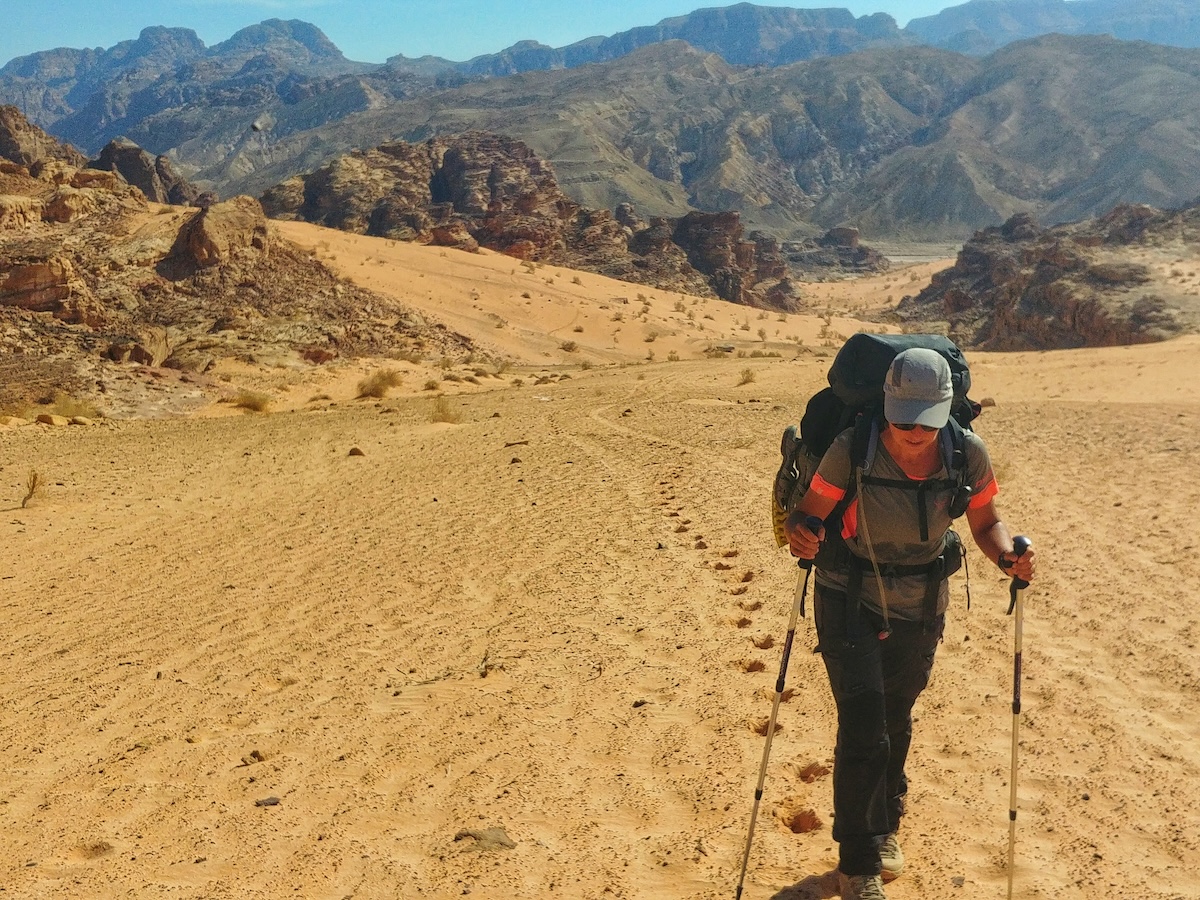 Escursionista con zaino cammina nel deserto di sabbia della Giordania